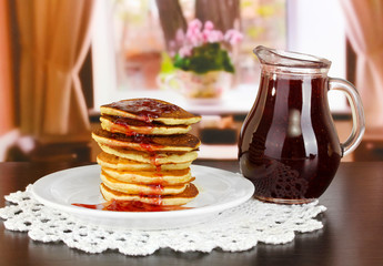 Sweet pancakes on plate with jam on table in room