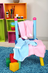 Small and colorful chair with baby clothes