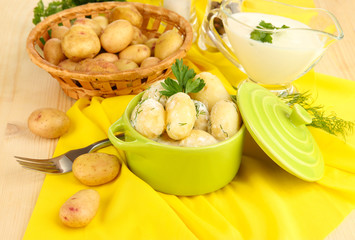 Tender young potatoes with sour cream and herbs in pan