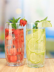 Glasses of fruit drinks with ice cubes on table in cafe