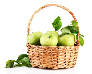 Juicy green apples with leaves in basket, isolated on white