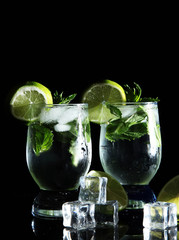 Glasses of cocktail with ice on black background