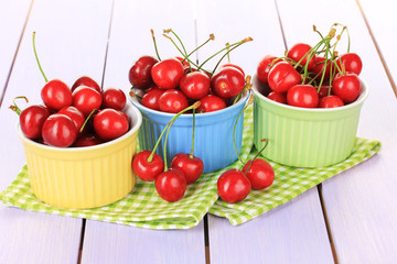 Cherry berries in bowls on wooden table close up