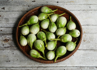 green eggplants   in the threshing basket on wooden table