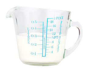 Measuring cup containing milk  isolated on white
