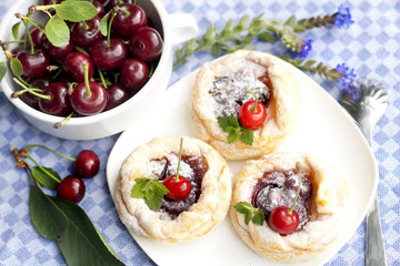 Puff pastry cakes with cherries on a white plate