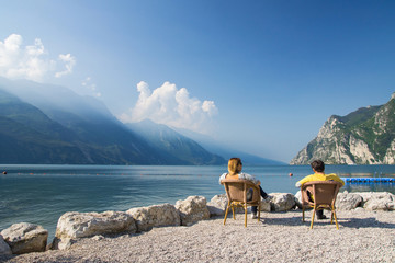 man and woman sitting at the lake garda, italien - obrazy, fototapety, plakaty