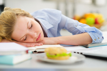Teenage girl fall asleep while studying in kitchen