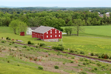 Fototapeta na wymiar Gorgeous red barn with railroad tracks in front of it