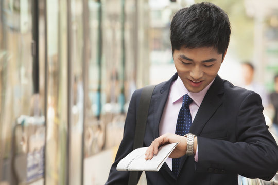 Young Businessman checking the time, waiting for the bus