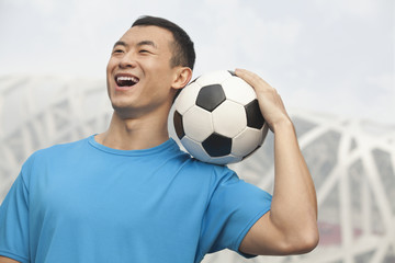 Young man holding soccer ball, Beijing