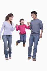 Obraz premium Family swinging child in mid-air, studio shot
