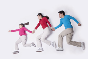 Naklejka premium Family holding hands and imitating running, studio shot