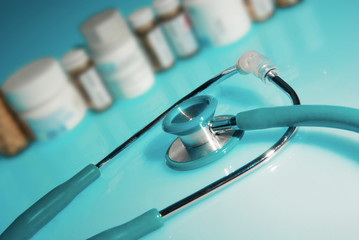 A stethoscope in front of medicine bottles on blue background