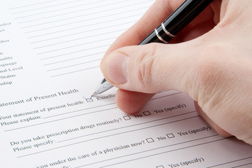 Hand filling in medical questionnaire form in a clipboard