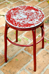 Old metal red chair on brick floor