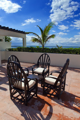 Chairs and little table on tropical terrace overlooking sea