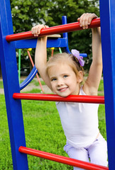 Fototapeta na wymiar Happy little girl on outdoor playground equipment