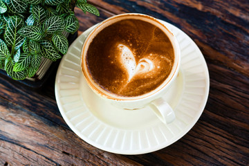 rusty cup of Capuchino coffee in a white cup with vintage pot on