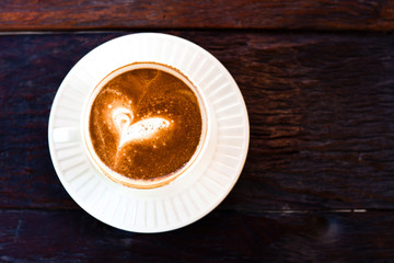 Rusty cup of Capuchino coffee in a white cup on wooden backgroun