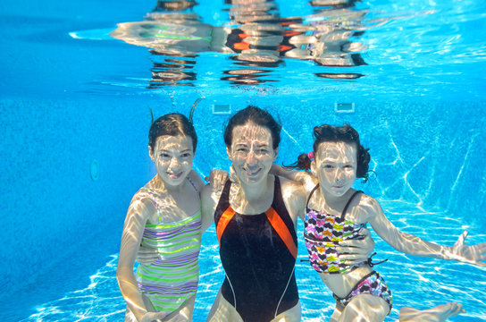 Family swim underwater in pool and having fun on vacation