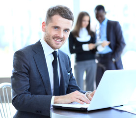 Business man sitting at his desk in the office with a laptop