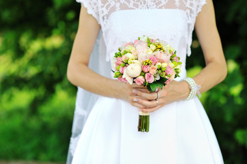 Obraz na płótnie Canvas Bride holding wedding bouquet in hands