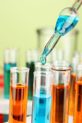 Laboratory pipette with drop of color liquid over glass test