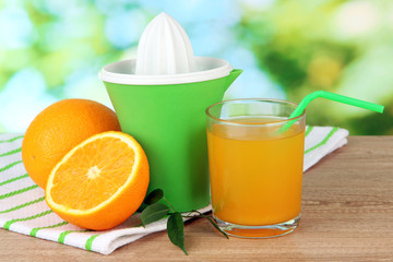Citrus press, glass of juice and ripe oranges