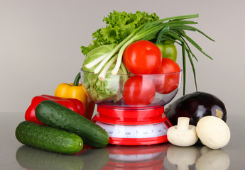 Fresh vegetables in scales on gray background