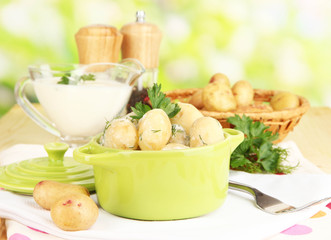 Tender young potatoes with sour cream and herbs in pan