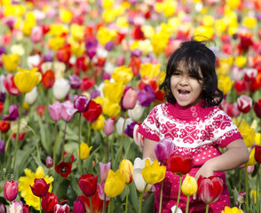 Obraz na płótnie Canvas Little Girl Playing in Tulip Field