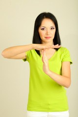 Girl showing time out sign on grey background
