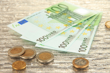 Euro banknotes and euro cents on grey glass background
