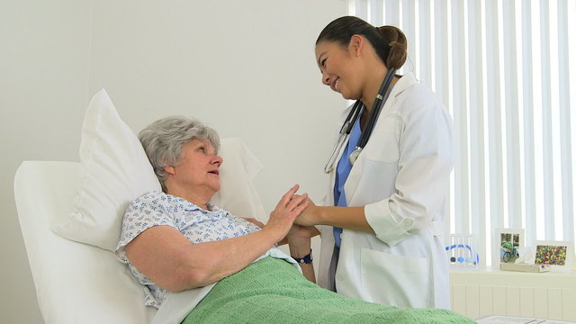 Asian female doctor giving support to elderly patient