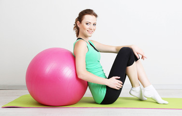Fototapeta na wymiar Portrait of beautiful young woman exercises with gym ball