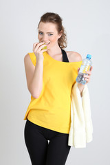 Beautiful young woman with bottle of water and apple