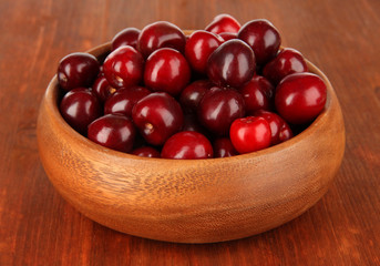 Cherry berries in bowl on wooden table close-up