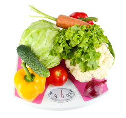Fresh vegetables on scales on grey background