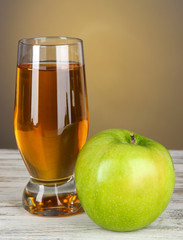 Glass of fresh apple juice on table on gray background