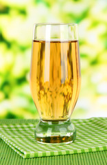 Glass of fresh apple juice on table on bright background