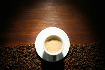 Cup of coffee with coffee beans on wooden background