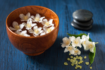 Fototapeta na wymiar White flowers in a bowl, stones for massage and sea salt. Spa.