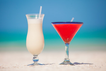 Two cocktails: pina colada and margarita on white sand beach