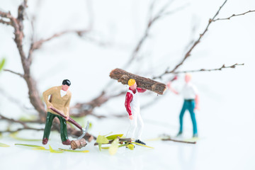 Miniature workmen working together in pruning and cutting trees