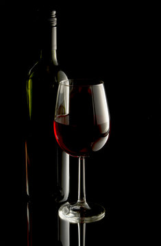 Low key image of red wine in glass with bottle