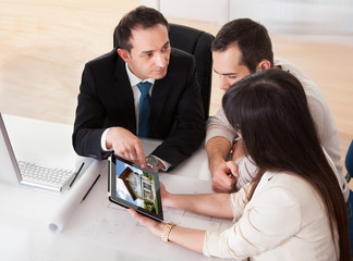 Happy Young Couple Discussing With Consultant