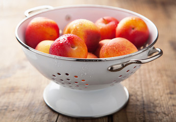 fresh nectarines and plums in colander