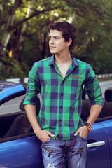 Handsome man with casual clothes posing near his car, outdoors p