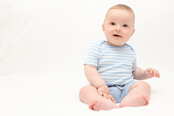 beautiful laughing happy baby boy sitting on white bed